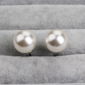 Elegant pair of white round pearl cufflinks with silver metal base on grey velvet tray