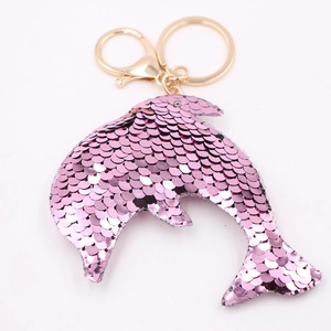 Sparkly pink sequin dolphin keychain with gold metal ring on white background