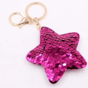 Macro shot of rose red sequined star keychain with gold metal clasp on white background