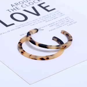 Macro view of C-shaped acrylic hoop earrings with tortoiseshell pattern on display card