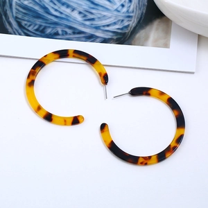 Detailed close-up of amber tortoiseshell acrylic C-hoop earrings with metal posts