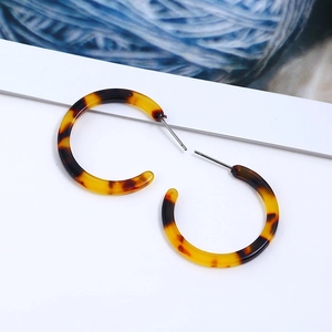 Close-up of tortoise shell pattern acrylic C-shaped hoop earrings on white background