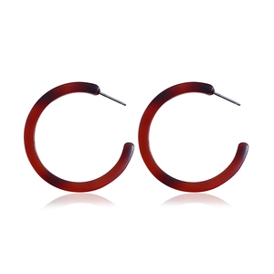 Macro shot of amber resin C-shape hoop earrings with metallic posts and soft reflections