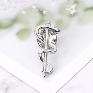 Macro shot of silver Rod of Asclepius medical brooch with butterfly clasp closure