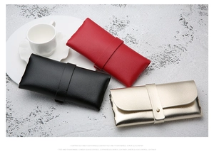 Three textured faux leather sunglasses cases in red, black, and champagne gold colors