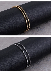 Detailed view of silver and gold stainless steel box chains on a textured display
