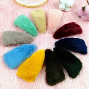 Flat lay of 12 colorful triangle plush hair clips arranged in a circle on a pink background