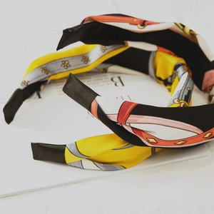 Detail of silk-satin knotted headband featuring colorful luxury chain and strap patterns
