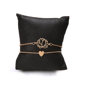 Ensemble de bracelets en or rose avec breloques lotus et cœur sur coussin noir