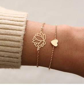Détail de l'ensemble de bracelets avec breloques lotus évidé et cœur sur poignet féminin
