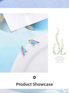 Detailed close-up of colorful enamel bird stud earrings on a white ceramic edge
