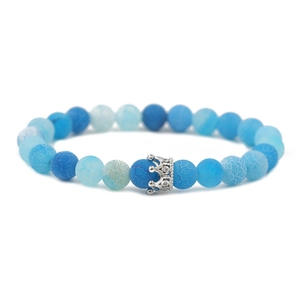 Macro detail of blue weathered stone beads and silver crown charm with crystal inlay