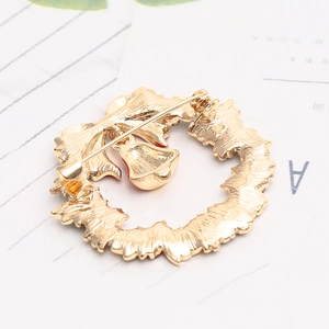 Close-up of golden Christmas wreath brooch back showing secure pin and safety clasp