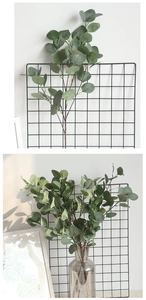 Detail of artificial eucalyptus stems in a glass vase with realistic grey-green leaves