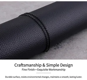 Close-up of a minimalist black stainless steel chain link necklace on textured leather