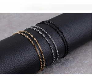 Close-up of O-link chain necklaces in gold, silver, and black on a leather stand