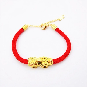 Vue détaillée du pendentif gourde en or rose sur bracelet tressé rouge avec fermoir