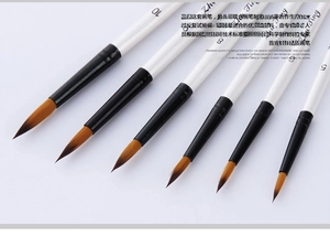 Close-up of pearl white handles and brown nylon tips on professional watercolor brushes