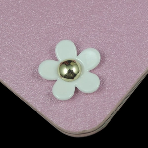 Détail macro d'une marguerite en résine blanche sur un accessoire en cuir rose