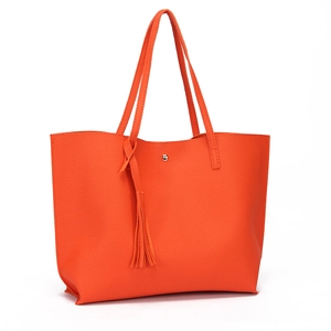 Detailed close-up of orange litchi-textured tote bag with tassel and magnetic buckle
