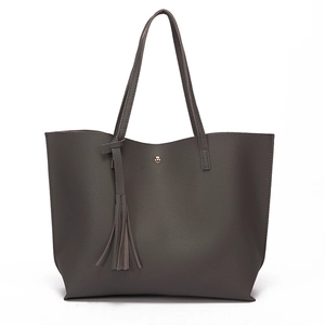 Close-up of dark grey lychee pattern leather tote bag with tassel and magnetic buckle