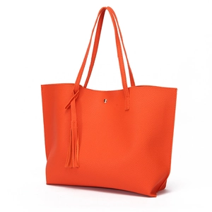 Detail of orange tote bag with lychee texture and stylish matching tassel pendant