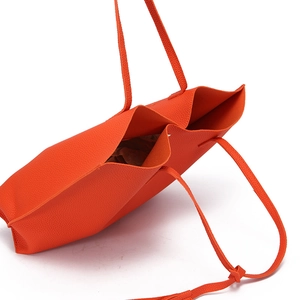 Top view of bright orange pebbled leather tote bag showing spacious interior and texture