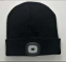 Detail of the integrated LED light on a black knitted beanie for outdoor use
