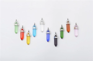 Close-up of ten hexagonal crystal point pendants in various colors with silver bails
