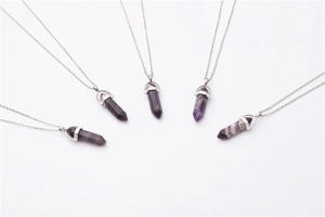 Detailed view of five purple quartz point pendants with silver chains in a fan layout