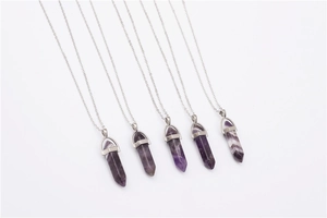 Set of six purple hexagonal quartz point necklaces with silver chains on white background