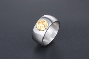 Close-up of titanium steel ring with a golden bird relief on a silver band
