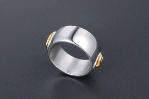 Macro shot of silver titanium steel ring with a gold flying bird crest on dark background