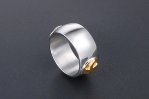 Macro shot of silver titanium wide ring band featuring an embossed golden cross detail