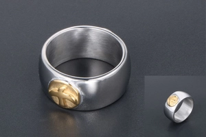 Macro detail of silver titanium ring with gold cross emblem on wide band surface