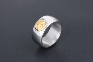 Macro view of wide silver ring band featuring a detailed golden flying bird relief icon