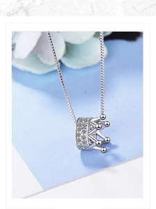 Close-up of a silver crown necklace pendant with sparkling rhinestones and box chain