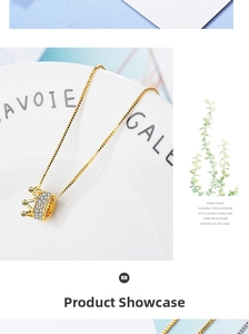 Detailed close-up of a golden crown pendant necklace with sparkling white crystals