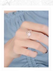 Close-up of elegant silver open ring featuring a delicate pink cherry blossom on a model finger
