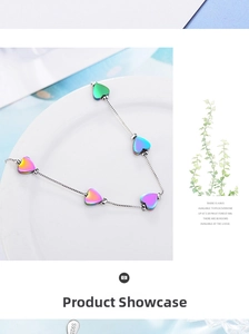 Macro shot of S925 silver heart bracelet with colorful gradient heart pendants on ceramic