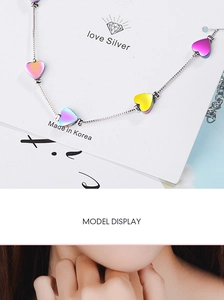 Detail of a silver chain necklace with gradient iridescent heart-shaped charms