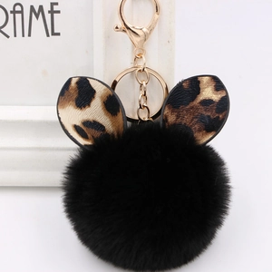 Close-up of black plush pom pom keychain with leopard print ears and gold metal clasp