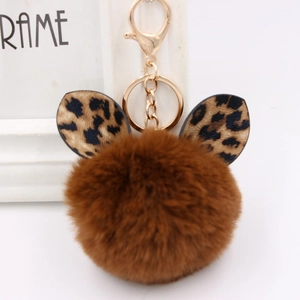 Close-up of leopard print ears on a brown plush ball keychain with a gold metal clasp
