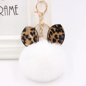 Close-up of white plush pompom keychain with leopard print ears and gold metal clip