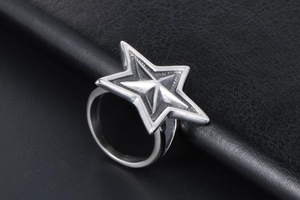 Close-up of a bold silver five-pointed star punk ring on black textured leather background