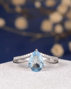 Elegant pear-cut light blue gemstone ring with V-shaped pavé diamond band in silver