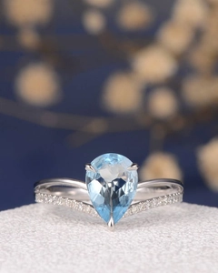 Macro shot of pear cut blue sapphire ring with a V-shaped chevron diamond band