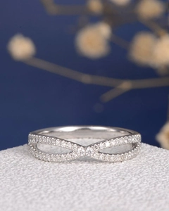 Macro shot of an infinity cross ring featuring white zircons on a dark blue background