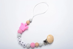 Detail of baby pacifier clip with pink crown, wooden beads, and BABY letter beads