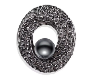 Detailed view of gunmetal bow brooch featuring dark crystals and a large black pearl